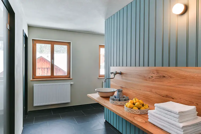 Badezimmer mit Waschtisch aus Holz und Emailschüssel