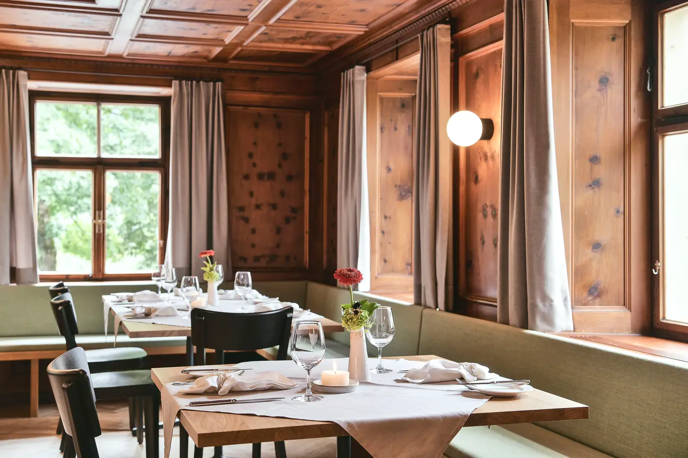 Holzgetäfelte Stube mit gedeckten Tischen und Fensterplätzen