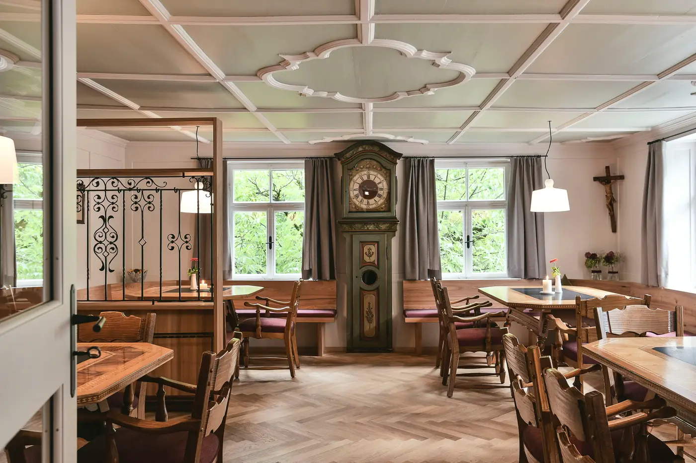 Stube mit bemalter Standuhr, Stuckdecke und Holztischen